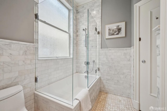 full bathroom with tile walls, plenty of natural light, toilet, and tiled shower / bath