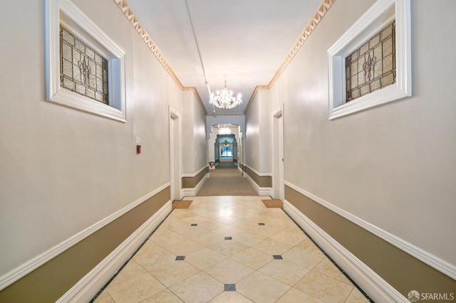 hallway with tile patterned flooring, crown molding, an inviting chandelier, baseboards, and arched walkways
