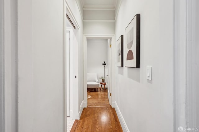 hall featuring crown molding, baseboards, and wood finished floors