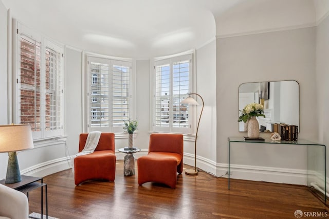 living area featuring baseboards, crown molding, and wood finished floors