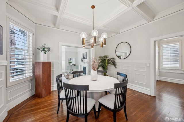 dining area with dark wood-type flooring, coffered ceiling, a decorative wall, and an inviting chandelier