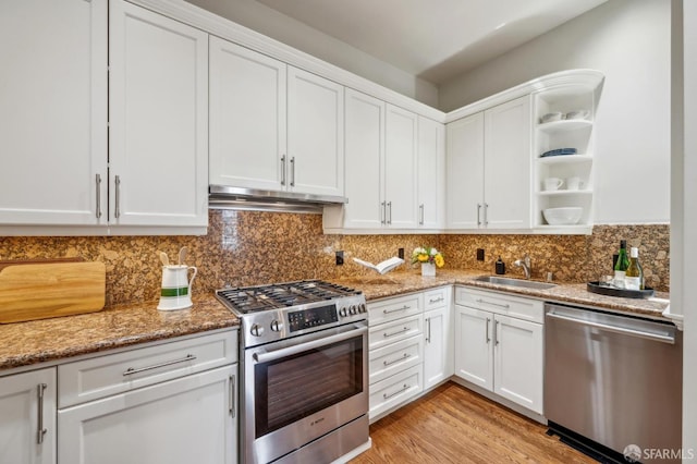 kitchen featuring open shelves, under cabinet range hood, white cabinets, a sink, and stainless steel appliances