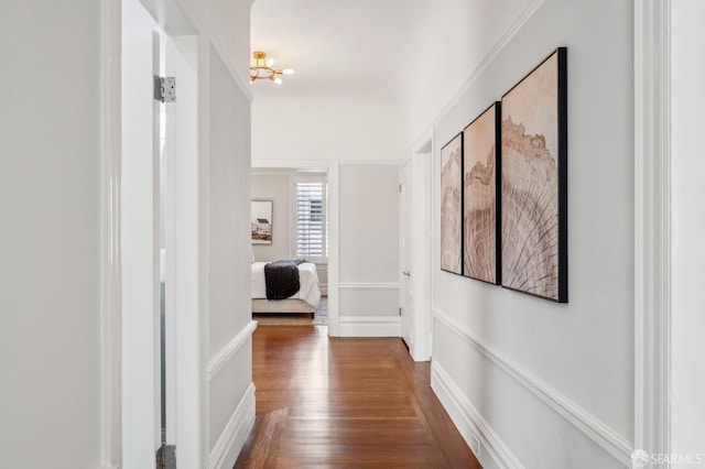 hall with dark wood-style floors and a chandelier