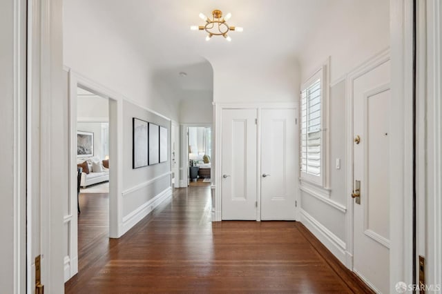 foyer featuring baseboards, a chandelier, and dark wood-style floors