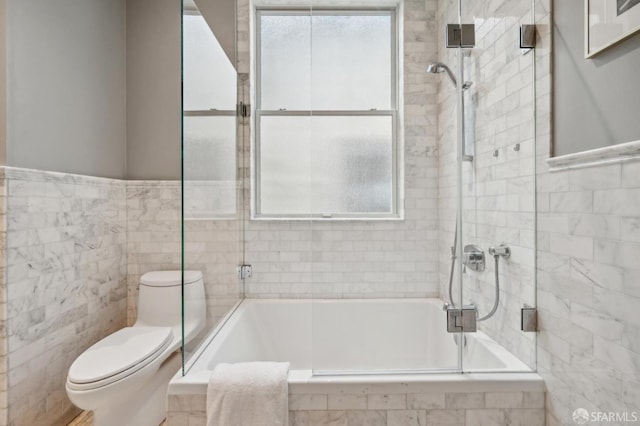 bathroom featuring toilet, tiled shower / bath, and tile walls