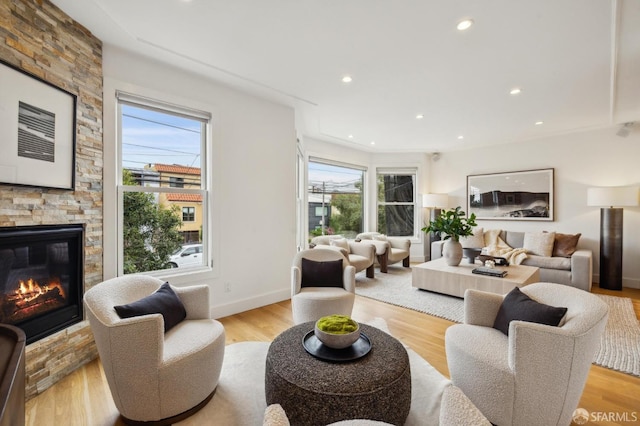 living room with a stone fireplace, plenty of natural light, and light hardwood / wood-style floors