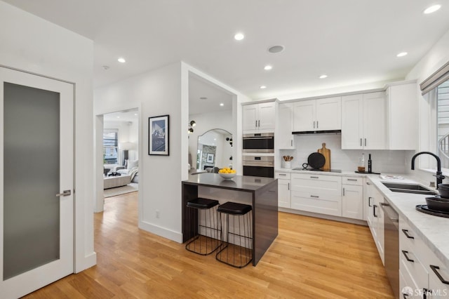 kitchen featuring white cabinetry, sink, stainless steel appliances, and light hardwood / wood-style floors