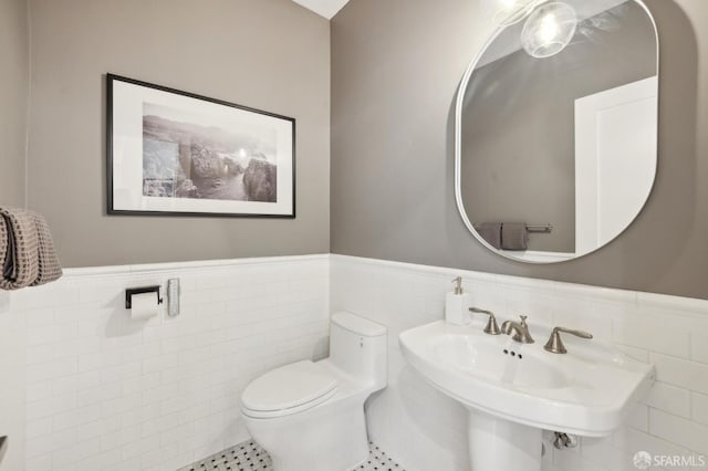 bathroom featuring toilet, sink, and tile walls