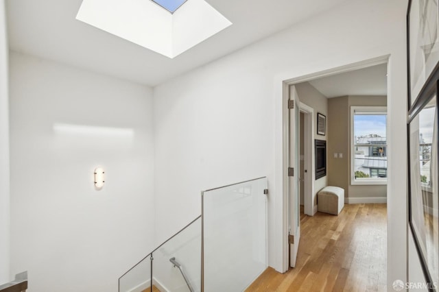 hallway featuring light hardwood / wood-style floors and a skylight