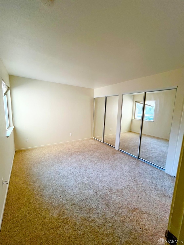 unfurnished bedroom with carpet flooring and multiple closets