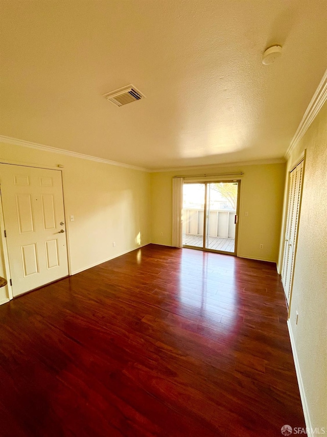 empty room featuring dark hardwood / wood-style flooring, a textured ceiling, and ornamental molding