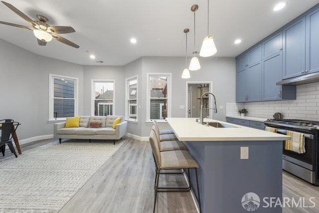 3004 26th St, San Francisco, CA 94110 - kitchen featuring stainless steel gas stove, a sink, blue cabinetry, decorative backsplash, and light wood-type flooring