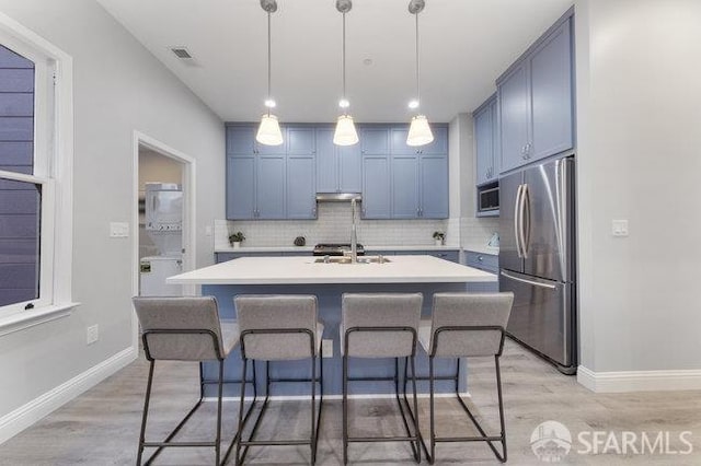 3004 26th St, San Francisco, CA 94110 - kitchen with stainless steel appliances, blue cabinetry, light countertops, backsplash, and a kitchen breakfast bar