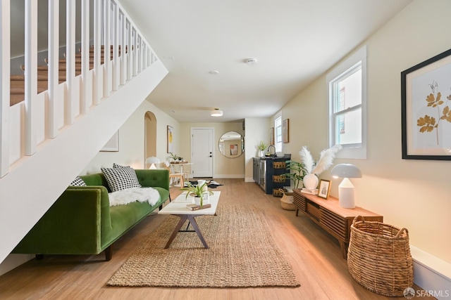 living room with baseboards, arched walkways, and wood finished floors