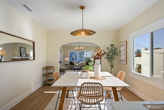 dining room with a chandelier, wood finished floors, visible vents, and baseboards