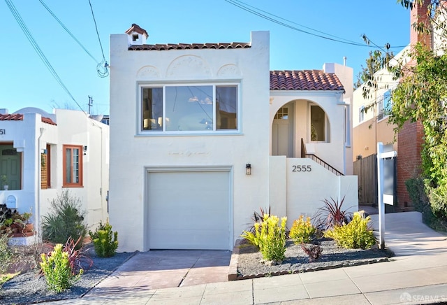 mediterranean / spanish-style house with a garage, concrete driveway, a tiled roof, and stucco siding