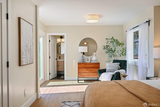 bedroom featuring wood finished floors, connected bathroom, and baseboards