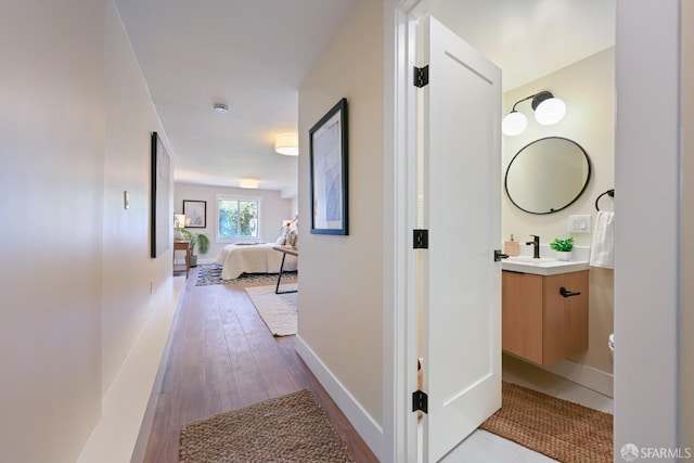 hall with a sink, baseboards, and wood finished floors