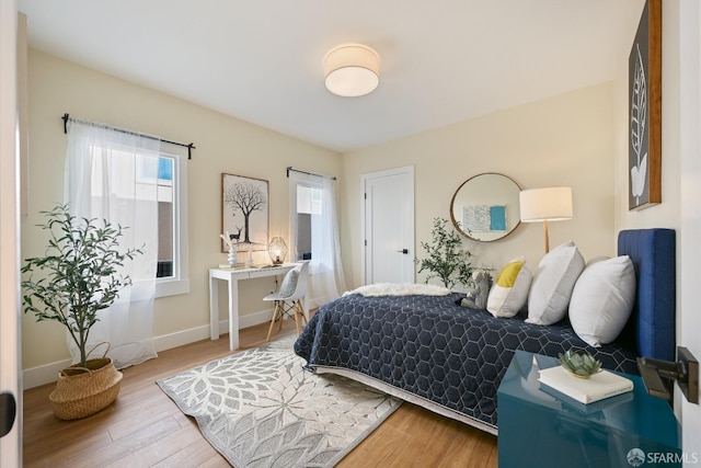 bedroom with multiple windows, baseboards, and wood finished floors