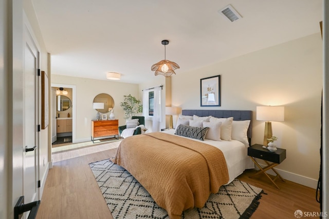 bedroom featuring wood finished floors, visible vents, and baseboards