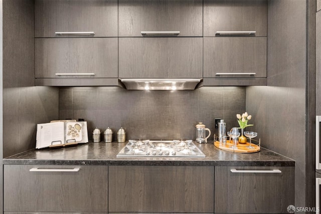 interior space featuring range hood, dark countertops, backsplash, gas cooktop, and modern cabinets