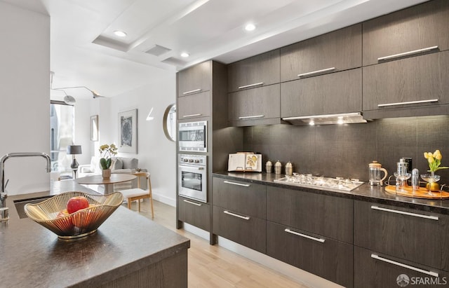 kitchen with stainless steel appliances, dark countertops, visible vents, and under cabinet range hood