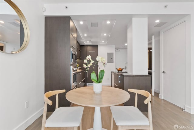 dining area with light wood finished floors, electric panel, baseboards, and recessed lighting