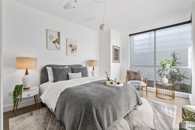 bedroom featuring a wall of windows, wood finished floors, and baseboards