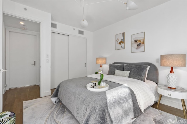 bedroom with a closet, visible vents, and wood finished floors