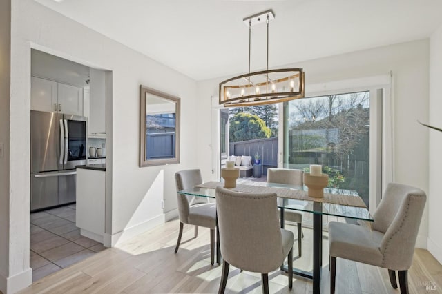 dining room with a chandelier, light wood-style flooring, and baseboards