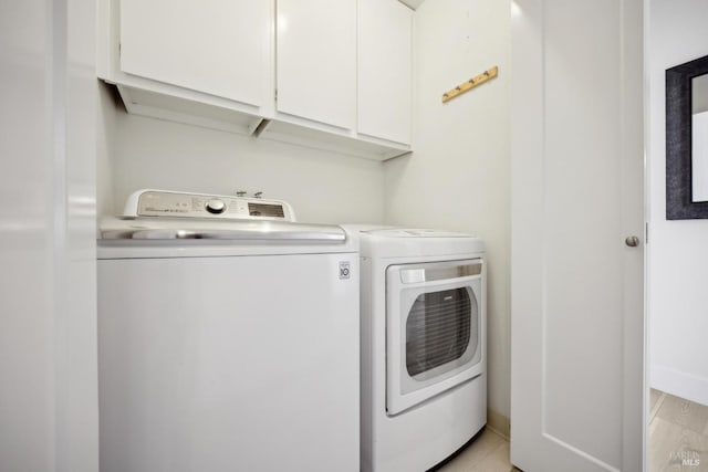 washroom with baseboards, cabinet space, and independent washer and dryer