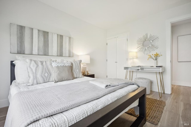 bedroom with wood finished floors, baseboards, and a closet