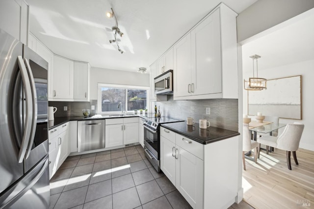 kitchen with a sink, dark countertops, backsplash, and stainless steel appliances