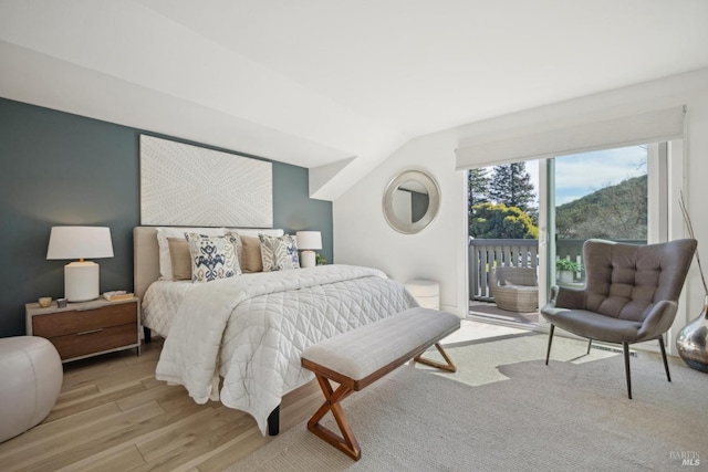 bedroom with vaulted ceiling, access to outside, and light wood-style floors