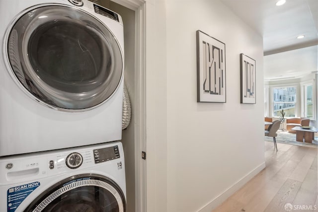 washroom featuring stacked washer / dryer, light wood-style flooring, recessed lighting, and baseboards
