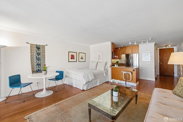 bedroom featuring stainless steel refrigerator, ornamental molding, and light wood-type flooring