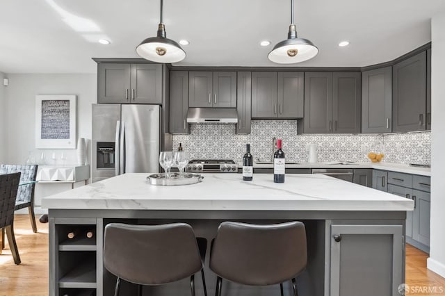 kitchen with light stone counters, gray cabinetry, stainless steel fridge with ice dispenser, a center island, and hanging light fixtures