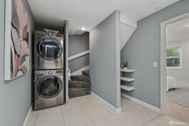 laundry area with light tile patterned floors and stacked washer and dryer