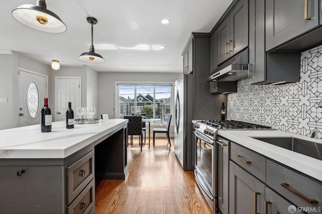 kitchen featuring backsplash, stainless steel gas range oven, pendant lighting, light hardwood / wood-style flooring, and gray cabinets