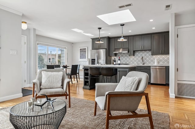 living room with a skylight, light hardwood / wood-style flooring, and sink