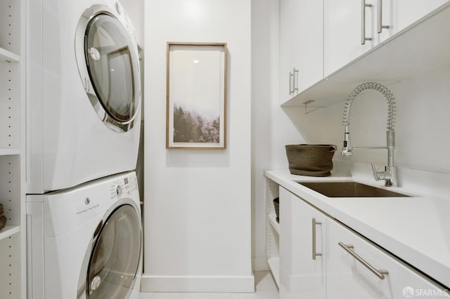 clothes washing area featuring stacked washer / dryer, sink, light tile patterned floors, and cabinets