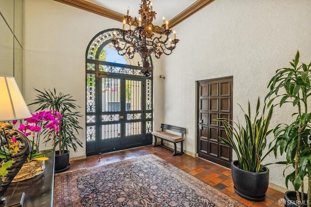 foyer with ornamental molding, french doors, and a notable chandelier