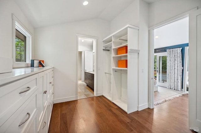 interior space with baseboards, wood finished floors, and lofted ceiling