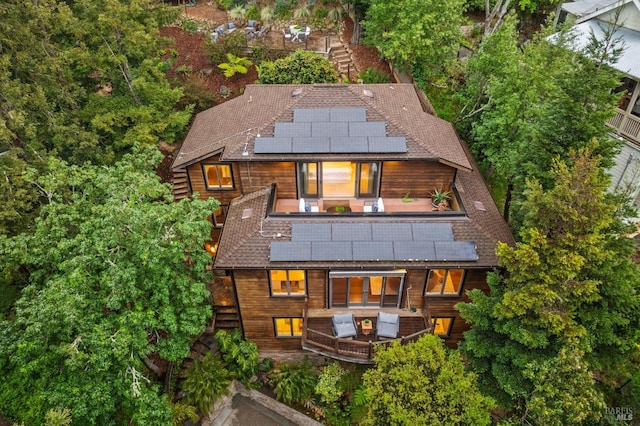 rear view of house featuring roof mounted solar panels, roof with shingles, stairway, and a balcony