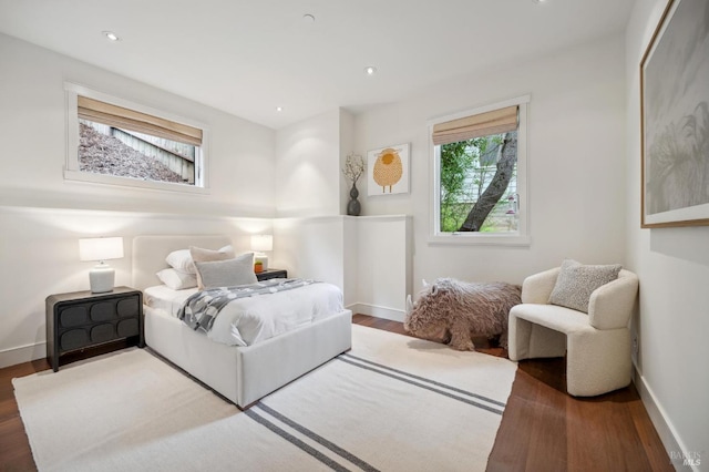 bedroom with baseboards, wood finished floors, and multiple windows
