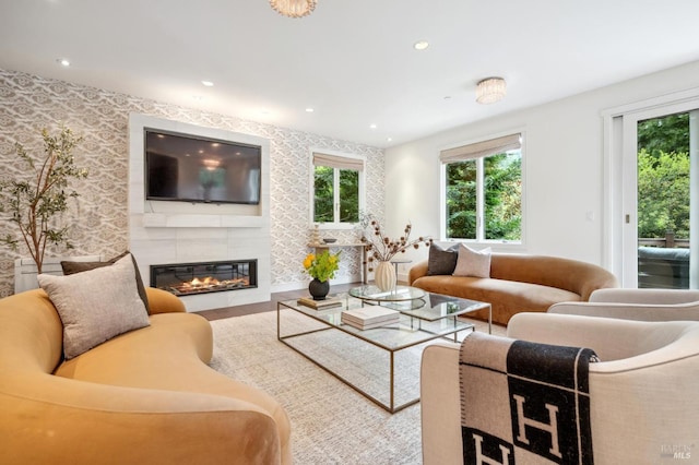 living room featuring plenty of natural light, recessed lighting, a glass covered fireplace, and wood finished floors