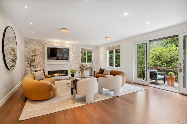 living room featuring a glass covered fireplace, a wealth of natural light, and wood finished floors