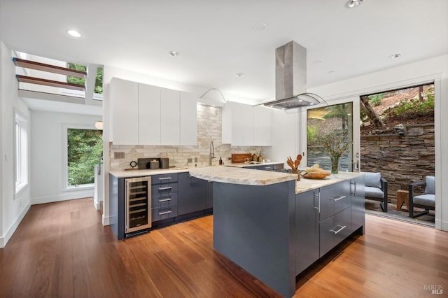 kitchen with modern cabinets, white cabinets, beverage cooler, and island range hood