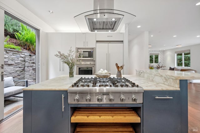 kitchen featuring built in appliances, recessed lighting, wood finished floors, and open floor plan