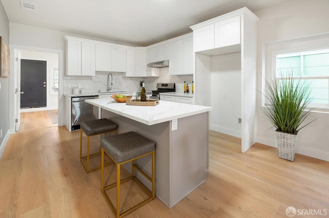 830 47th St, Emeryville, CA 94608 - kitchen with appliances with stainless steel finishes, a sink, range hood, light wood-style floors, and a kitchen island